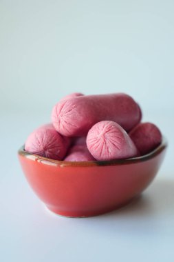 Mini Sausage in a red color bowl on white .