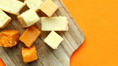 Cheese cubes green, yellow and red color on chopping board .