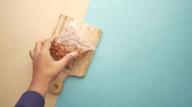 Erkeklerin üst görünümü bir paket badem fıstığı seçiyor. .