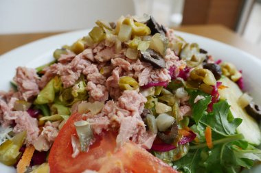 spoon pick tuna salad from a bowl on table .