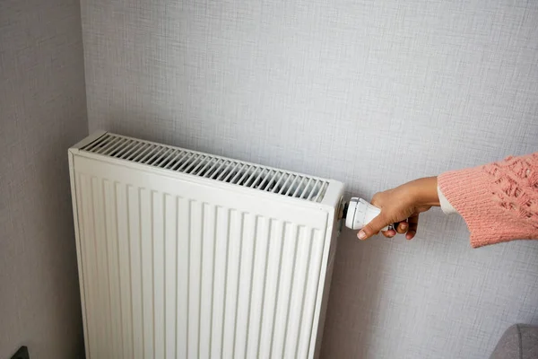 妇女用手调节散热器的温度 — 图库照片