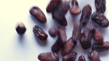 Beyaz arkaplana düşen tarih meyvelerinin yavaş çekimi .