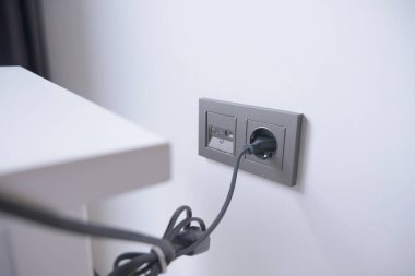  white color power cord cable plugged into wall .