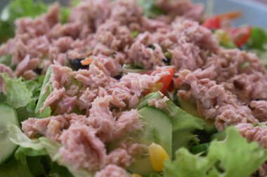 spoon pick tuna salad from a bowl on table .