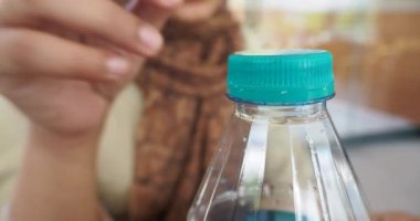 Plastik bir su şişesinin kapağını aç. .