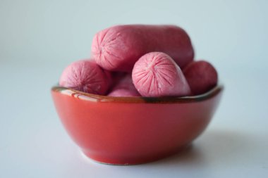 Mini Sausage in a red color bowl on white .