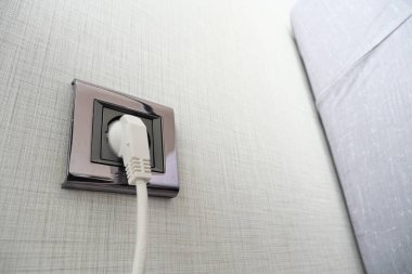  white color power cord cable plugged into wall .