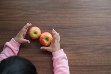  Çocuk eli ahşap masada elma tutuyor. .