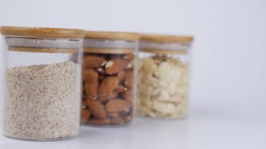 Badem fıstığı, toz ve dilimler beyaz arka planda bir kavanozda .