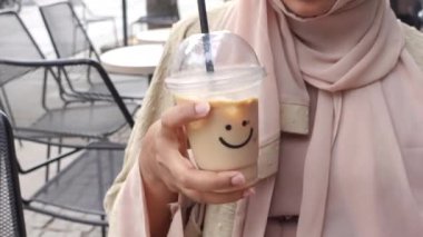 Plastik bir kapta soğuk kahve, üzerinde gülücük şekli tasarımı var. .