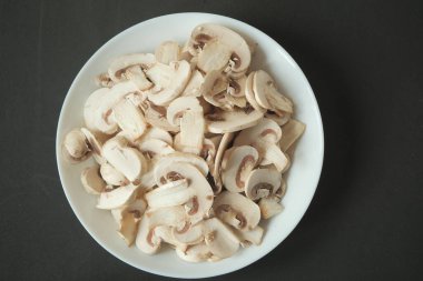 Fresh champignons mushroom in a white bowl on table ,
