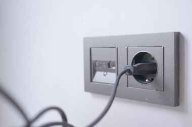  white color power cord cable plugged into wall .