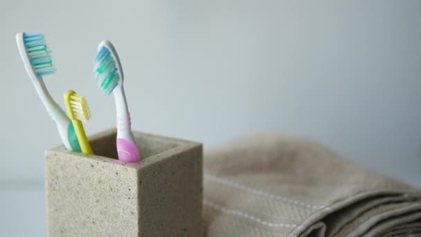 白いマグカップの中のカラフルな歯ブラシが壁に — ストック動画