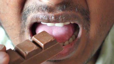 Genç adam siyah çikolata yiyor. .