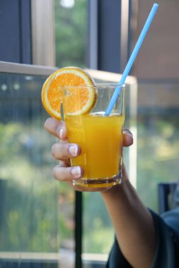 Bir bardak portakal suyunu doğa arka planına tutarak. .