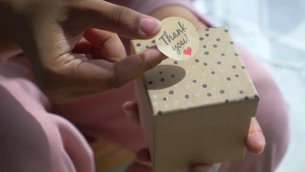 Γυναίκες Χέρι Βάζοντας Ένα Αυτοκόλλητο Ευχαριστώ Ένα Κουτί Δώρου — Αρχείο Βίντεο