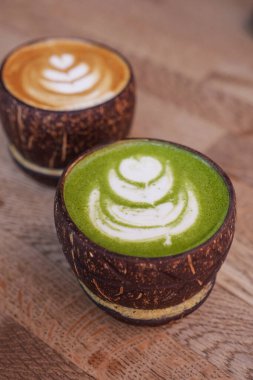 Latte ve matcha latte Hindistan cevizi bardağında masada. .