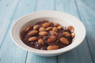 Koyu çikolatalı krema beyaza badem fıstığı döküyor. .