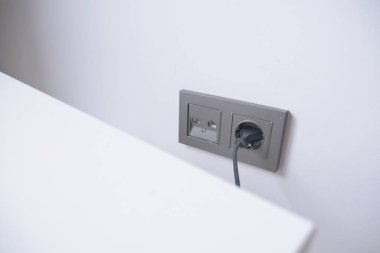  white color power cord cable plugged into wall .
