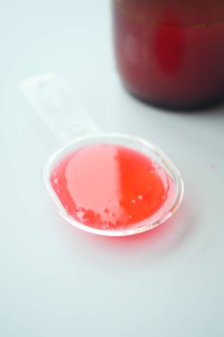  Beyaz arka planda plastik bir kaşıkta sıvı ilaç şurubu. .
