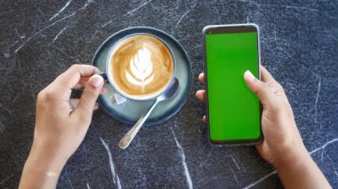 holding a cpu of coffee and using smart phone with green screen .
