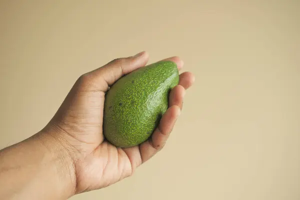Pov Van Het Houden Van Een Avocado Tegen Een Muur — Stockfoto