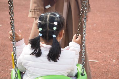  Çocuk parkta salıncakta sallanırken eğleniyor.