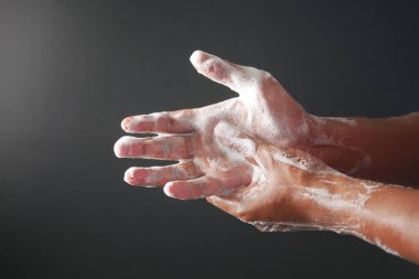 Genç adam ellerini sabunla sıcak suyla yıkıyor..