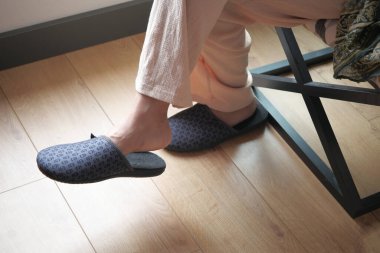 Evde yumuşak terlikli bir kadın var..