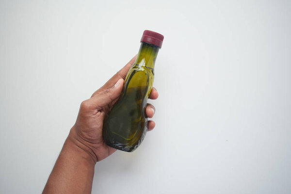 hand holding a bottle of olive oil .