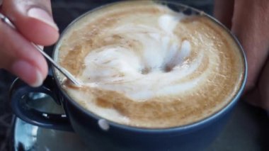 İnsan, kaşıkla kahve karıştırır.