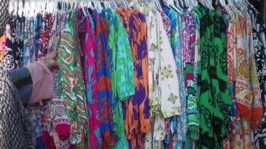 Kadın dükkanda kıyafet seçiyor.
