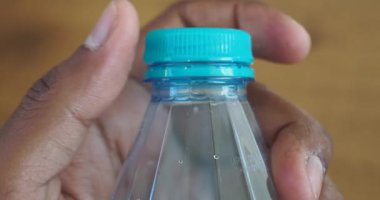 Plastik bir su şişesinin kapağını aç. .