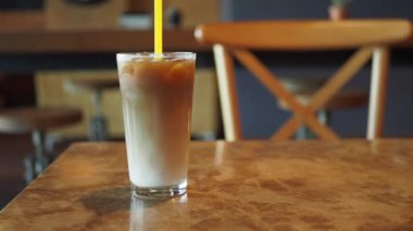 Dışarıdaki kafe masasında şeffaf bir bardakta buzlar eridi. ,