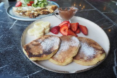 Taze böğürtlenli krep ve tabakta akçaağaç pekmezi.