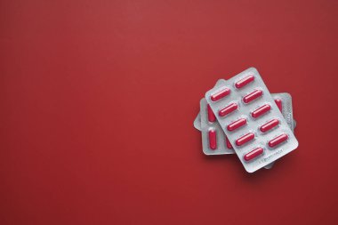 Kırmızı arka planda su toplayan hapların üst görünümü ,