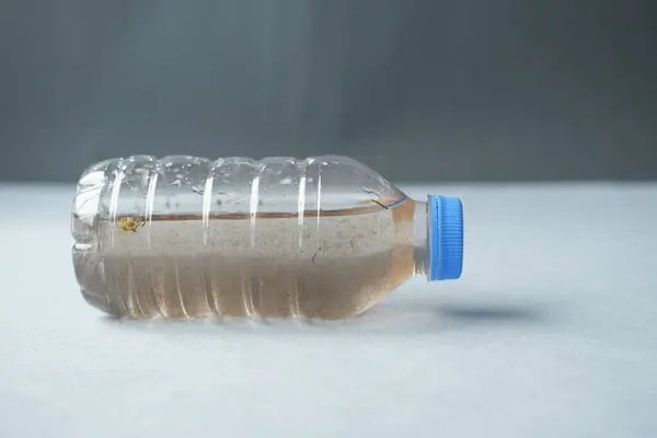 dirty bottle of plastic water on table .