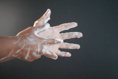 Genç adam ellerini sabunla sıcak suyla yıkıyor..