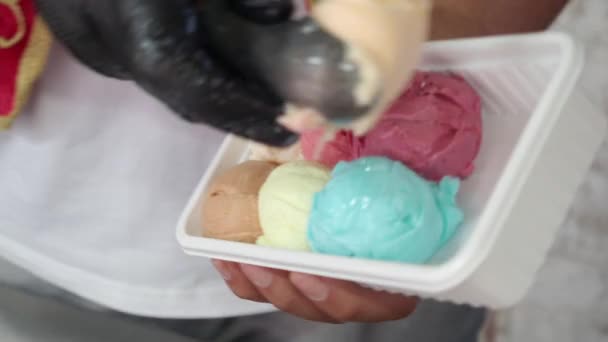 プラスチック容器に異なる風味のアイスクリームを置く男性 — ストック動画