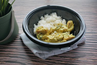 curry chicken and rice in a take away plastic packet on table .