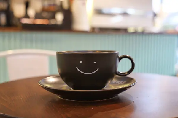 black coffee cup with smile shape design on it .