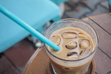 Dışarıdaki kafe masasında şeffaf bir bardakta buzlar eridi. ,