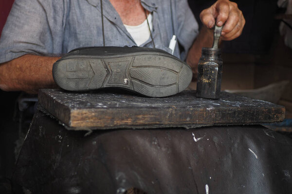  A cobblers hands mending shoe stitching with needle .