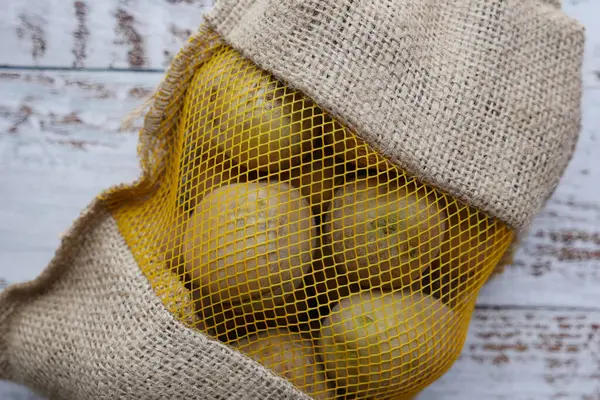 Close up of raw potatoes in a bag on table .