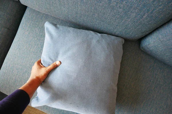 hand keeping put pillow on sofa, cleaning sofa .