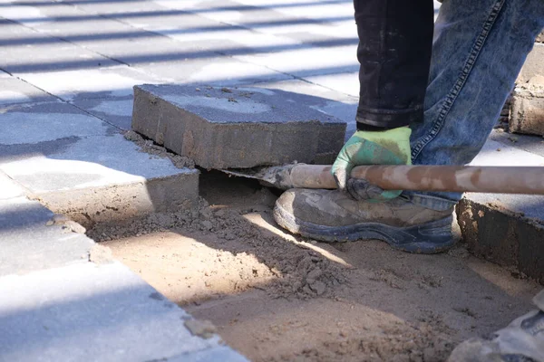 Worker remove large concrete blocks on a sandy surface