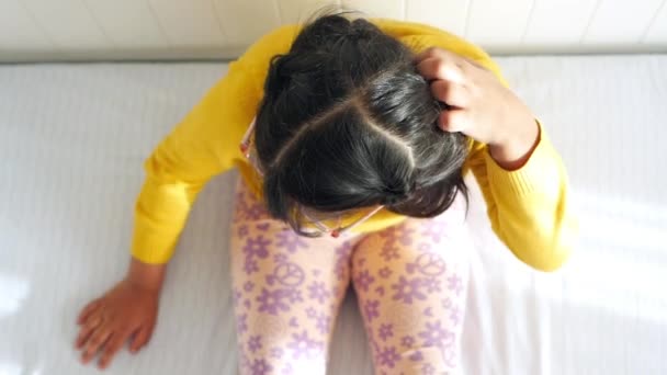 ベッドに座っている子供の頭を傷つけるトップビュー — ストック動画