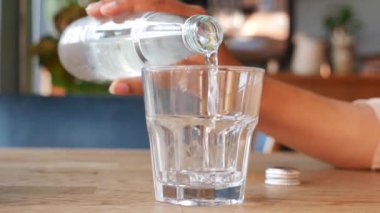 Masadaki bardakta şişeden su akıyor. ,