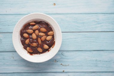Koyu çikolatalı krema beyaza badem fıstığı döküyor. .
