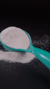 Siyah arka planda bebek sütü tozu ve kaşığı kapat.,